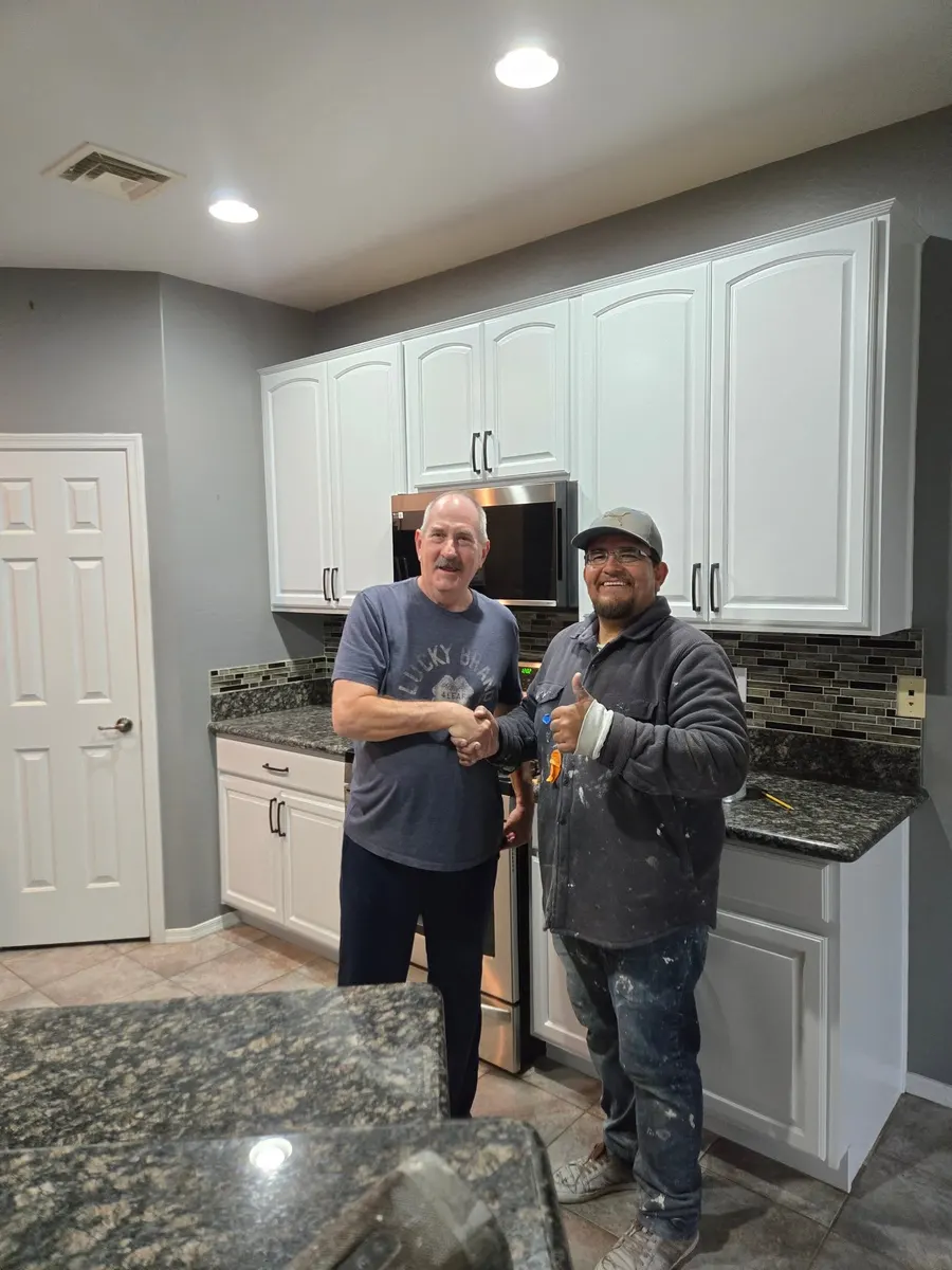 Kitchen with freshly painted white cabinets and a happy homeowner