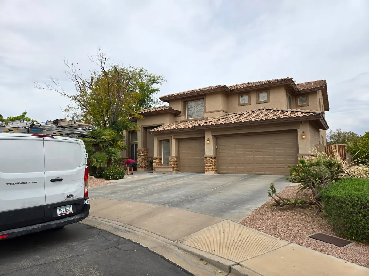 Tan two-story stucco home with fresh paint on body, trim and garage doors